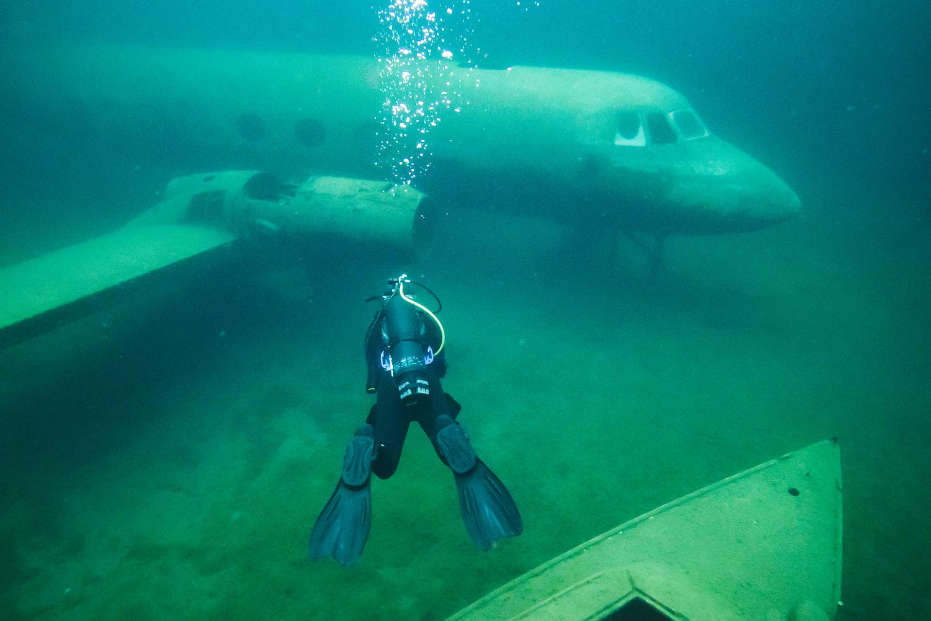 Scuba diver using an Avelo System exploring a submerged airplane in the clear quarry water at Gilboa Quarry.