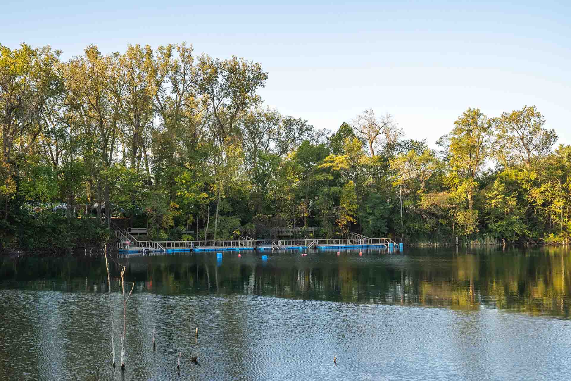 Dive platforms and docks at Gilboa Quarry scuba diving site with calm clear water and wooded shoreline